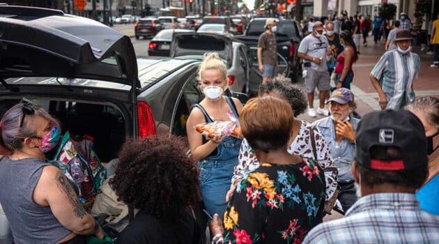 Lex Lindell, center, of New Orleans, hands out food and supplies to Hurricane Laura evacuees