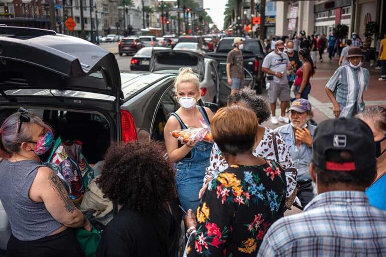 Lex Lindell, center, of New Orleans, hands out food and supplies to Hurricane Laura evacuees