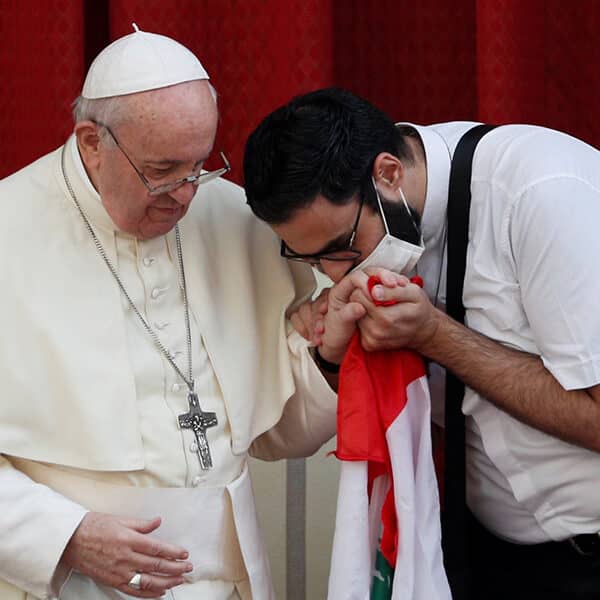 A masked Maronite Father Georges Briedi kisses the hand of Pope Francis