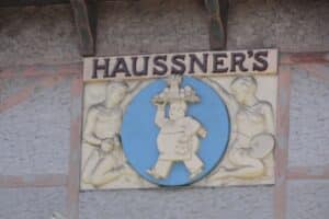 Sculpture relief with Haussner's printed on it and a man carrying a platter of food