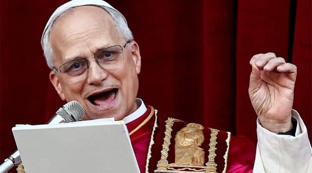 Pope Leo smiles as he speaks into a microphone