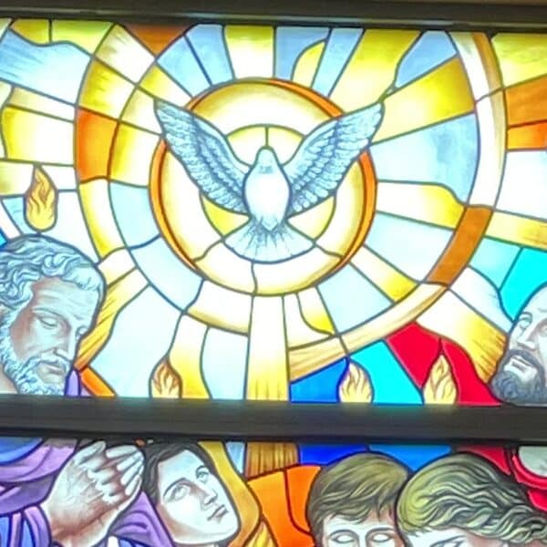 Stained glass window depicting a dove and some of the apostles with flames over their heads