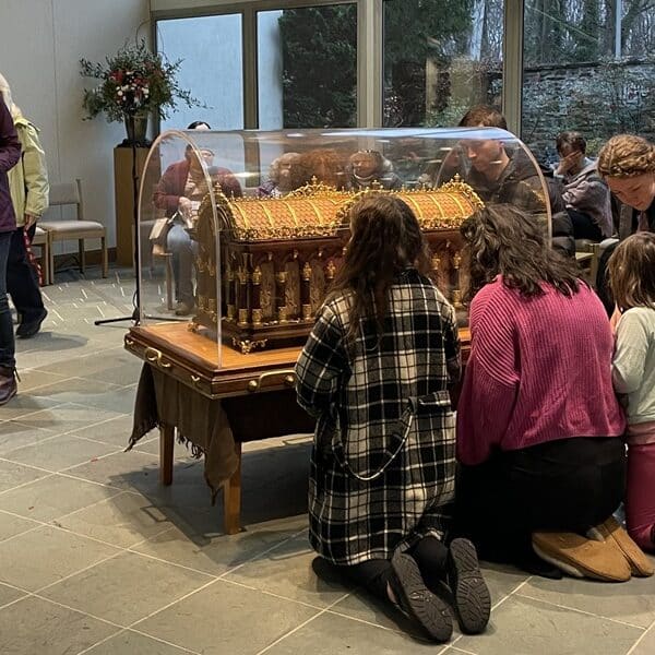 People kneel around St. Therese's relics in the chapel at the Carmelite Monastery