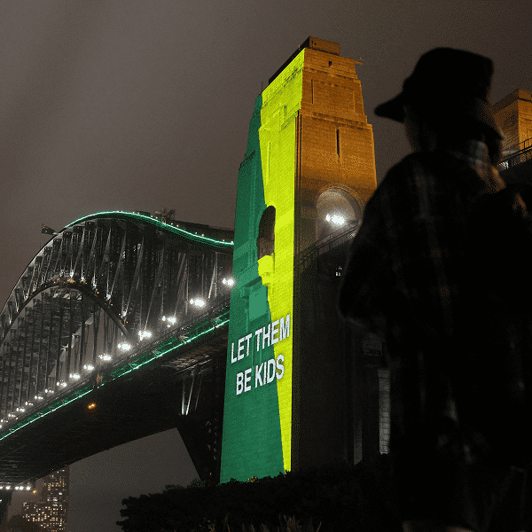 A message the reading "Let them be kids" is projected onto the Sydney Harbor Bridge