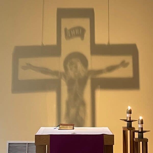 The shadow of a crucifix is shown on the wall of a chapel
