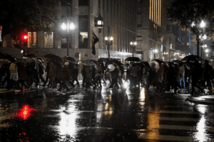 People holding umbrellas in the rain attend a protest against U.S. Immigration and Customs Enforcement