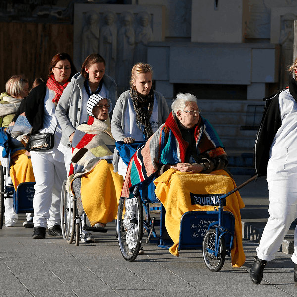 Caregivers push the sick and disabled at the Shrine of Our Lady of Lourdes