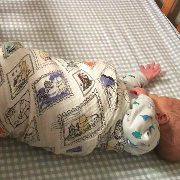 Baby wrapped in a blanket lies in crib