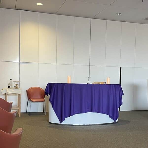 A purple cloth covers an altar against a white wall in the front of a room