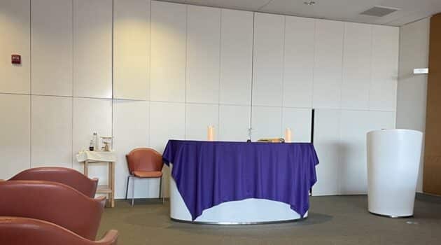 A purple cloth covers an altar against a white wall in the front of a room