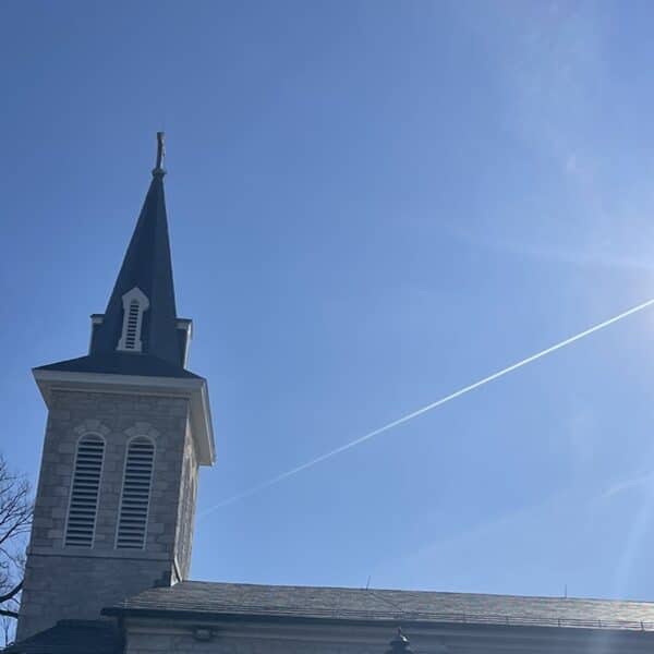 Church steeple against a blue sky with the shining sun