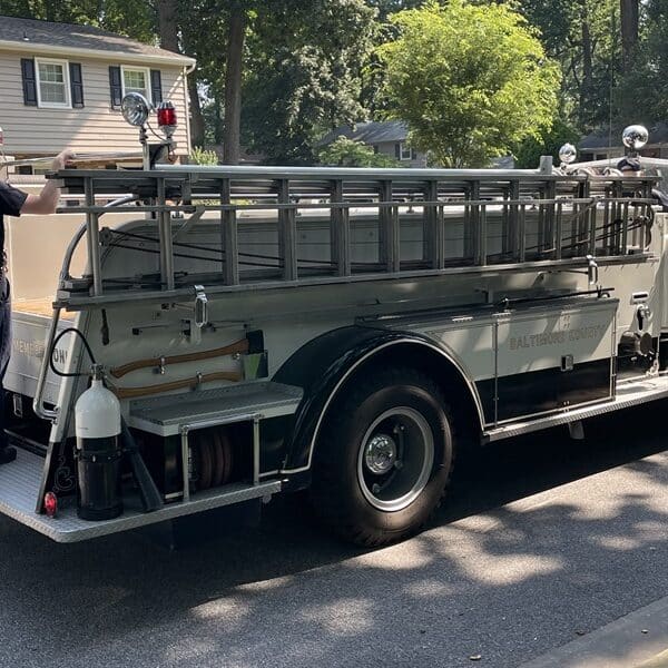 Firefighter rides on the back of a vintage fire engine