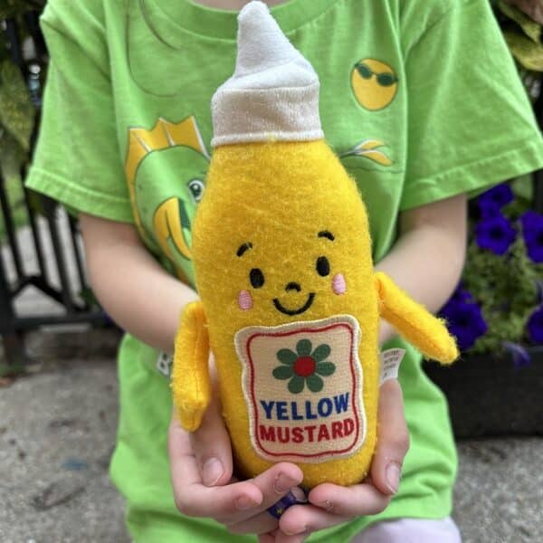 A child holds a plush mustard figure