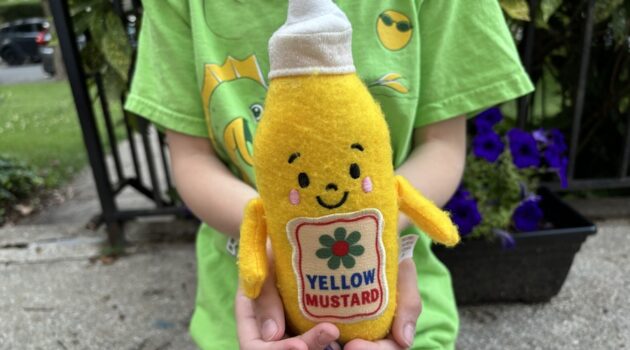 A child holds a plush mustard figure