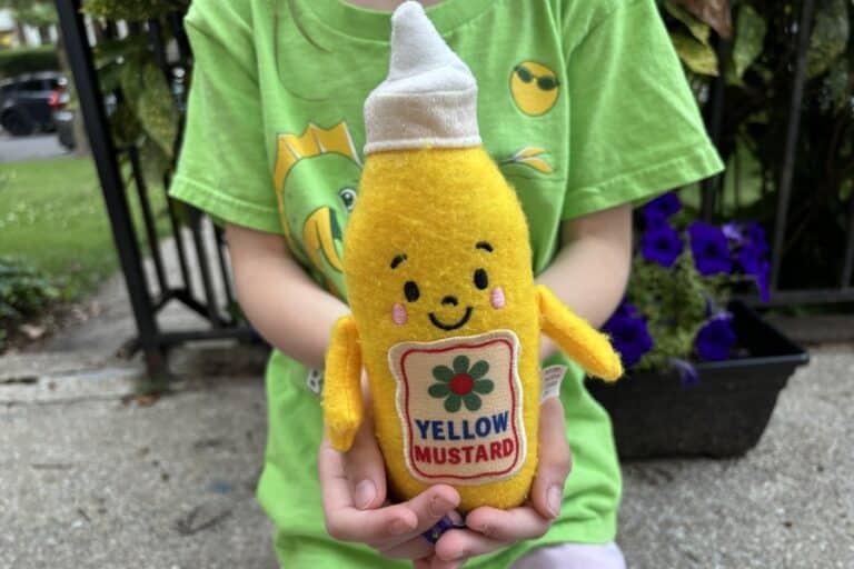 A child holds a plush mustard figure